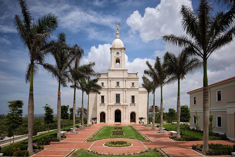 Exterior photo of the Latter-Day Saints temple. Palm trees line the landscaped brick walkways leading to the entrance.