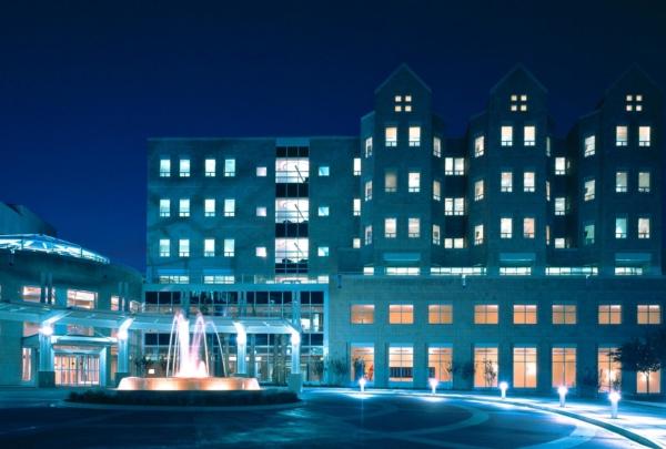 欧胜儿童医院的夜景照片. 蓝色的灯光和喷泉周围的砖圈驱动.